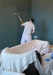 Decorator using rollers to paint a wall